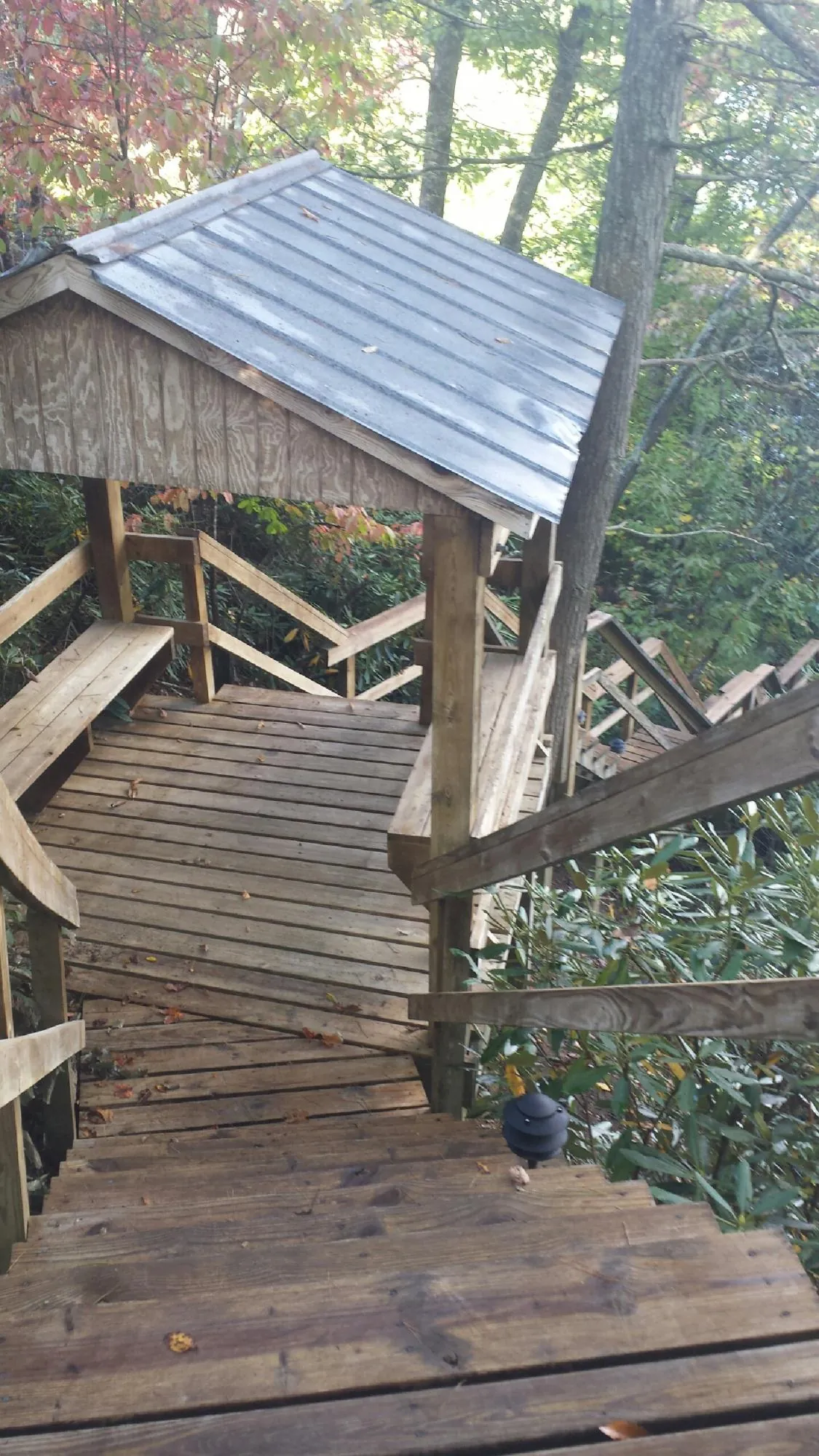 Metal roofed shelter over wooden steps on a wooded walkway — Skylight Repair & Installation work by our crew in Tremont